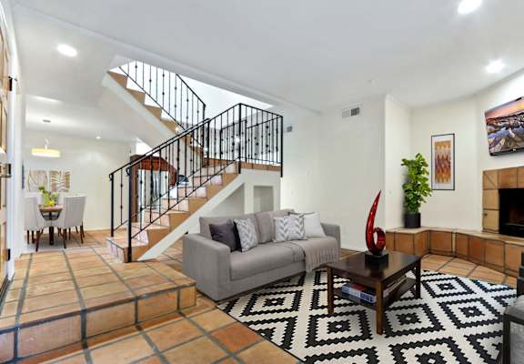 the living room of a house with a staircase in the background