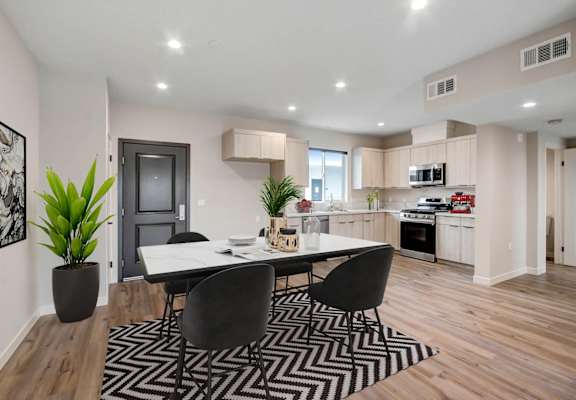 a dining area with a table and chairs and a kitchen in the background