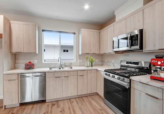a kitchen with light wood cabinets and stainless steel appliances