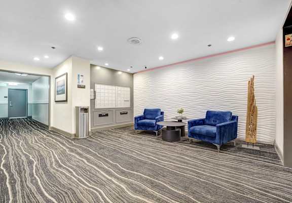 A waiting area with blue chairs and a wooden sculpture.