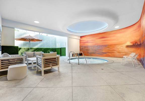 A modern outdoor seating area with a pool and a mural on the wall.
