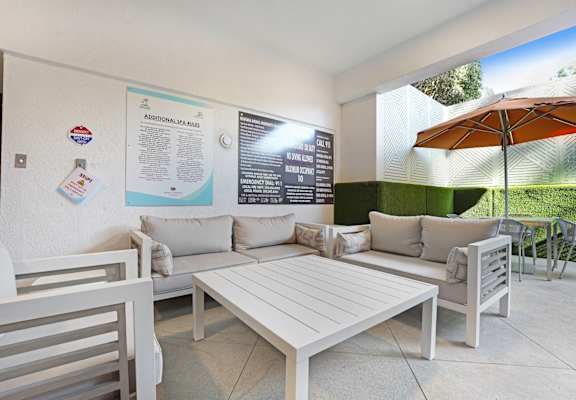 A white patio with a table and chairs and a poster on the wall.