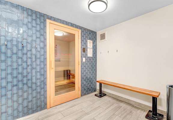 A room with a blue tile wall and a wooden bench.