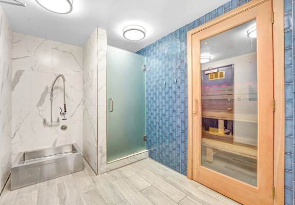 A bathroom with a marble wall and a glass shower door.
