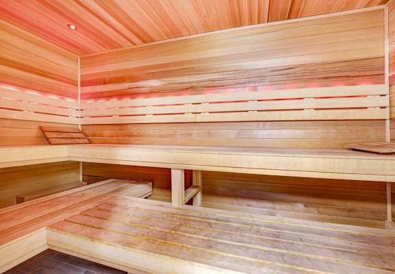 A wooden sauna with benches and a light on the ceiling.