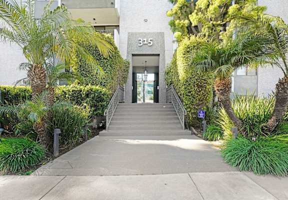 A concrete pathway leads to a glass door with the number 315 on it.