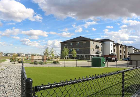 a view of a tennis court with apartments in the background at Upscale Living at the Grand off 45th, Fargo, 58104