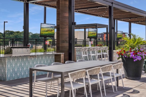 a patio with a wooden table and chairs and a bar with a grill