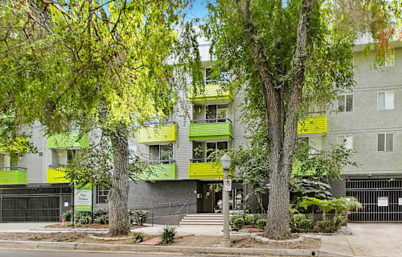 a building with green balconies and trees in front of it
