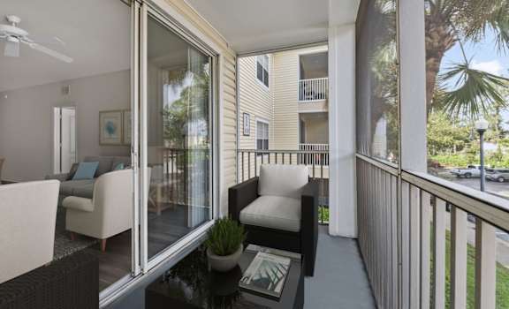 A balcony with a table and chairs overlooking a parking lot.