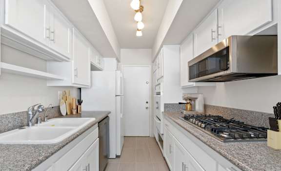 a kitchen with white cabinets and granite counter tops and a stove and microwave