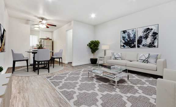 A living room with a white couch, a grey rug, and a ceiling fan.
