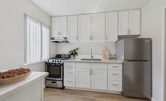 A kitchen with white cabinets and a stainless steel refrigerator.