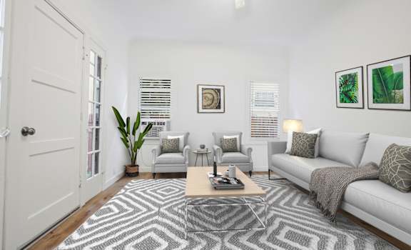 A living room with a grey couch, a coffee table, and a rug with a geometric pattern.