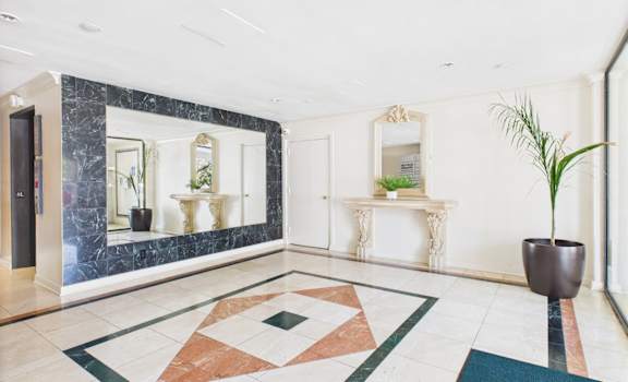 A hallway with a marble floor and a mirrored wall.