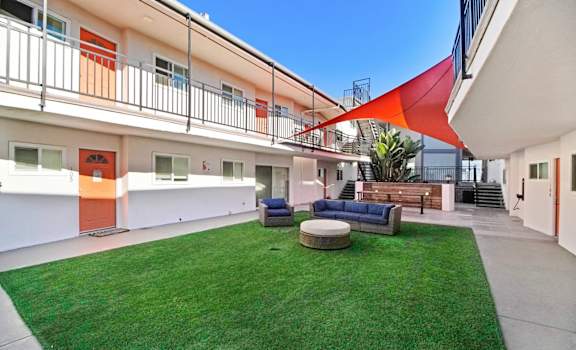 the courtyard of a building with green grass and furniture