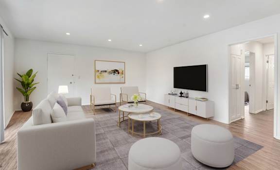 A modern living room with a white sofa, a coffee table, and a TV.