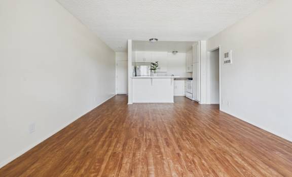 A long, empty room with wooden floors and white walls.