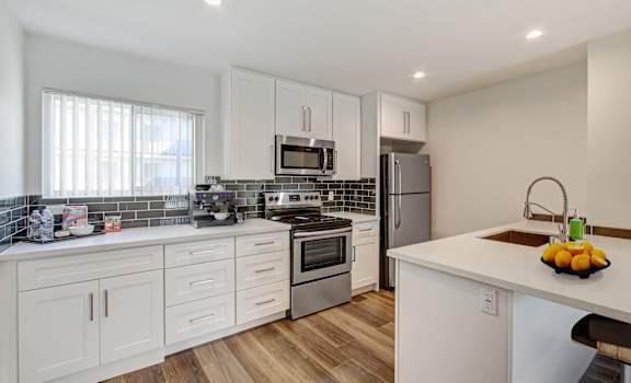 a kitchen with white cabinets and stainless steel appliances