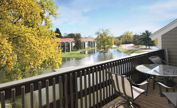 a balcony with a view of a lake and a table and chairs