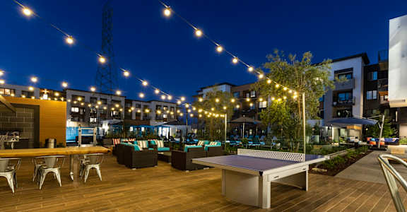 an outdoor patio with a ping pong table and lounge seating