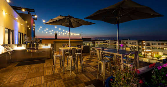 a rooftop bar with tables and chairs and umbrellas