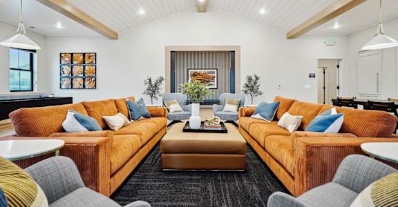 A living room with orange couches and a black rug.