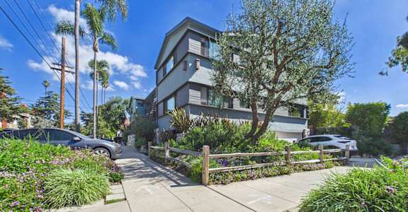 A modern two-story house with a grey exterior and a well-maintained garden in front.