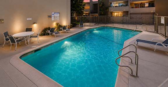 A swimming pool surrounded by chairs and a fence.