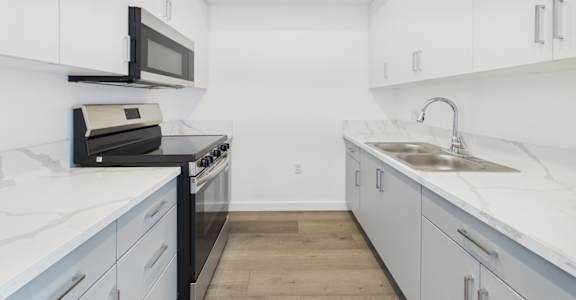 A kitchen with black appliances and white cabinets.