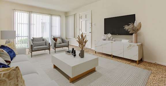 A living room with a white sofa, grey armchairs, a white coffee table, and a black television.