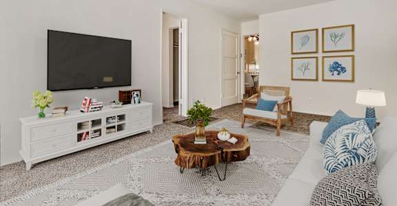 A living room with a white couch, a wooden coffee table, and a flat screen TV.