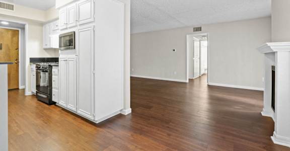 an empty living room with white cabinets and a wood floor