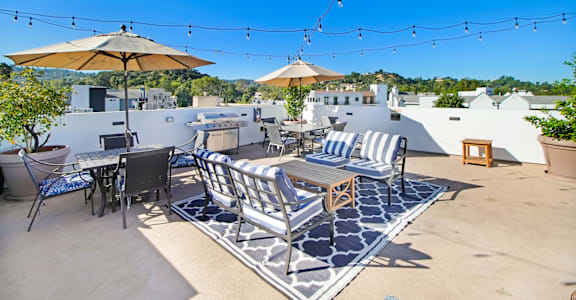 a patio with tables and chairs and umbrellas on a roof