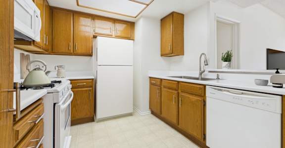 A kitchen with white appliances and wooden cabinets.
