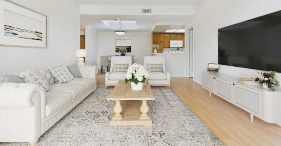 A living room with a white couch, a coffee table, and a television.
