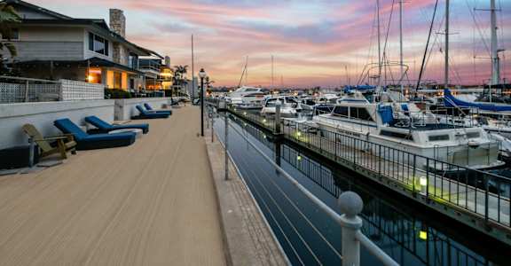 a marina at sunset with boats in the water and a house on the side of the