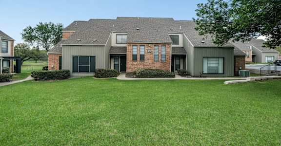 A house with a grey roof and a green lawn in front.
