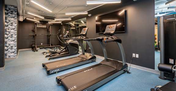 two treadmills and other exercise equipment in a gym with a tv