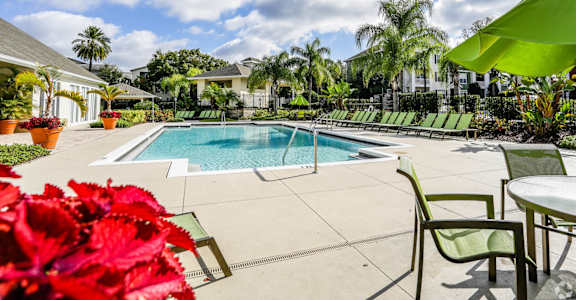 a swimming pool with green chairs and tables around it at The Arbor Walk Apartments, Tampa, FL 33617