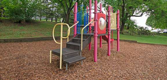 A playground with a slide, swings, and a seesaw.