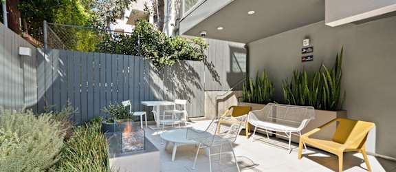 a patio with chairs and tables and a blue fence  at The Aster, Los Angeles, California