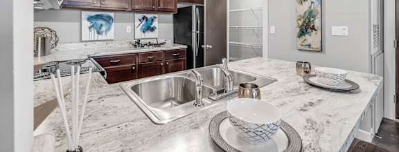 A modern kitchen with a marble countertop and stainless steel appliances.