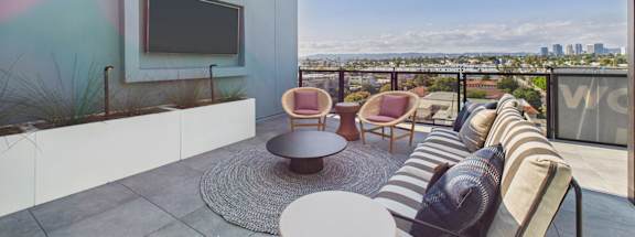 A balcony with a striped couch and a TV on the wall.