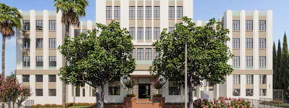 A large white building with a red brick base and a row of palm trees in front.