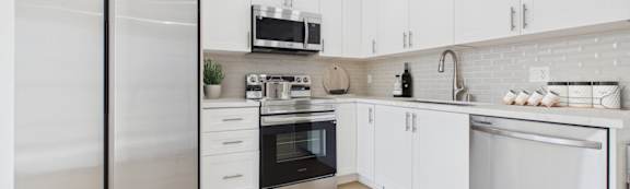 A modern kitchen with stainless steel appliances and white cabinets.