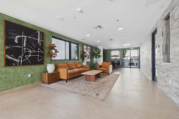 A living room with a green wall and a large abstract painting.