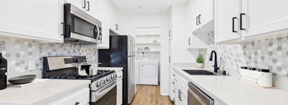 A kitchen with white cabinets and black appliances.