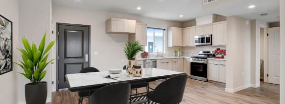 a dining area with a table and chairs and a kitchen in the background