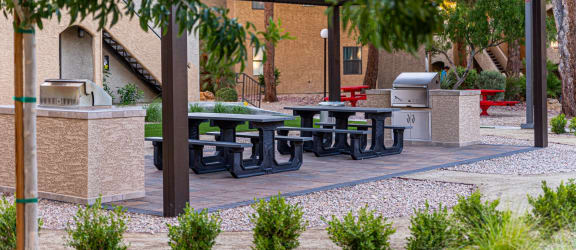 a picnic area with a grill and picnic tables